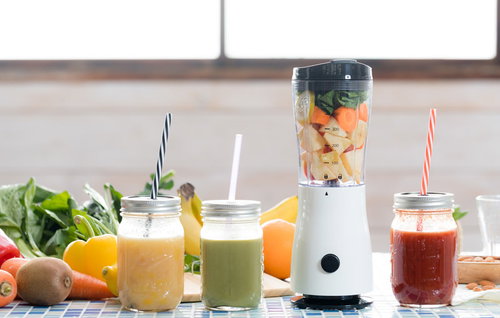 ジューサーに詰まったカット野菜と3種類のスムージー