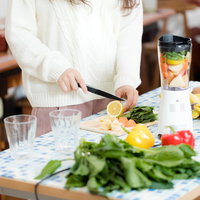 スムージー用に新鮮な果物をカットする女性の写真