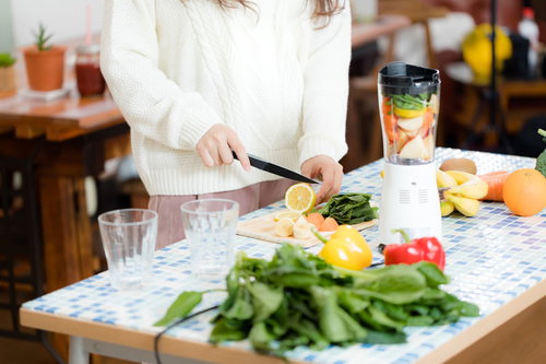 スムージー用に新鮮な果物をカットする女性