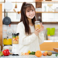 フルーツスムージーを手に笑顔のヘルシー女子の写真