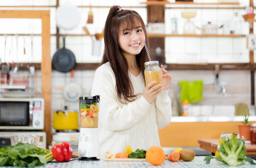 フルーツスムージーを手に笑顔のヘルシー女子