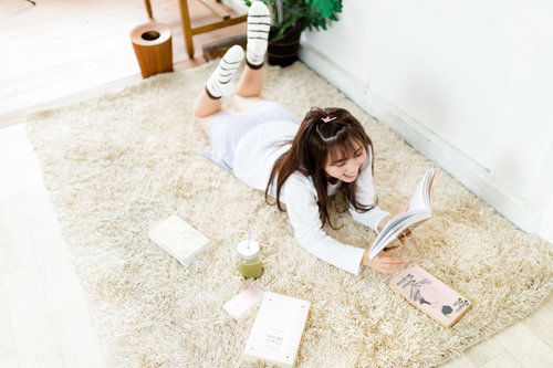 グリーンスムージーを飲みながら本を読む部屋着女性