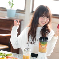 片手に赤い林檎を持ったスムージー好きな健康志向女子の写真