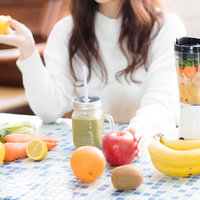 朝食テーブルに並ぶりんごと果物のグリーンスムージーの写真