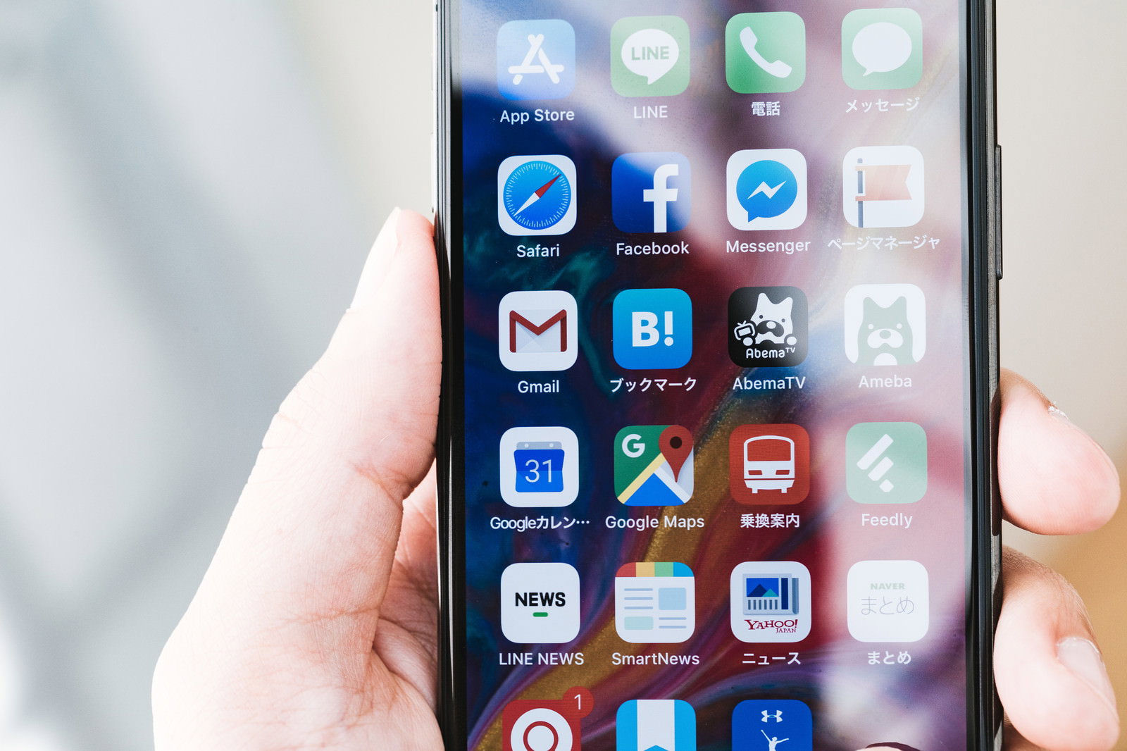 iPhoneのホーム画面を手で持つ女性