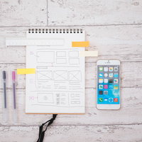 スマホとワイヤーフレームが書かれたノートでディレクションの写真