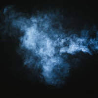 暗い背景に立ち上る薄く吐き出された白煙のスモークの写真