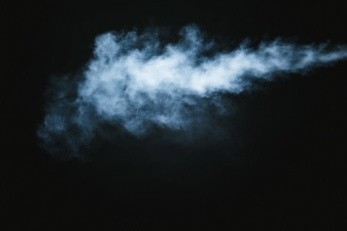 煙草のけむりが黒い背景に立ち込める白い煙