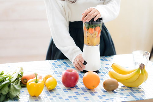 新鮮な果物と野菜をジューサーにかける様子