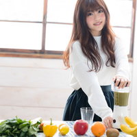 グリーンスムージーを作る若い女性と新鮮な野菜と果物の写真