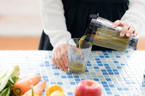 緑色のグリーンスムージーをグラスに注ぐ朝食風景
