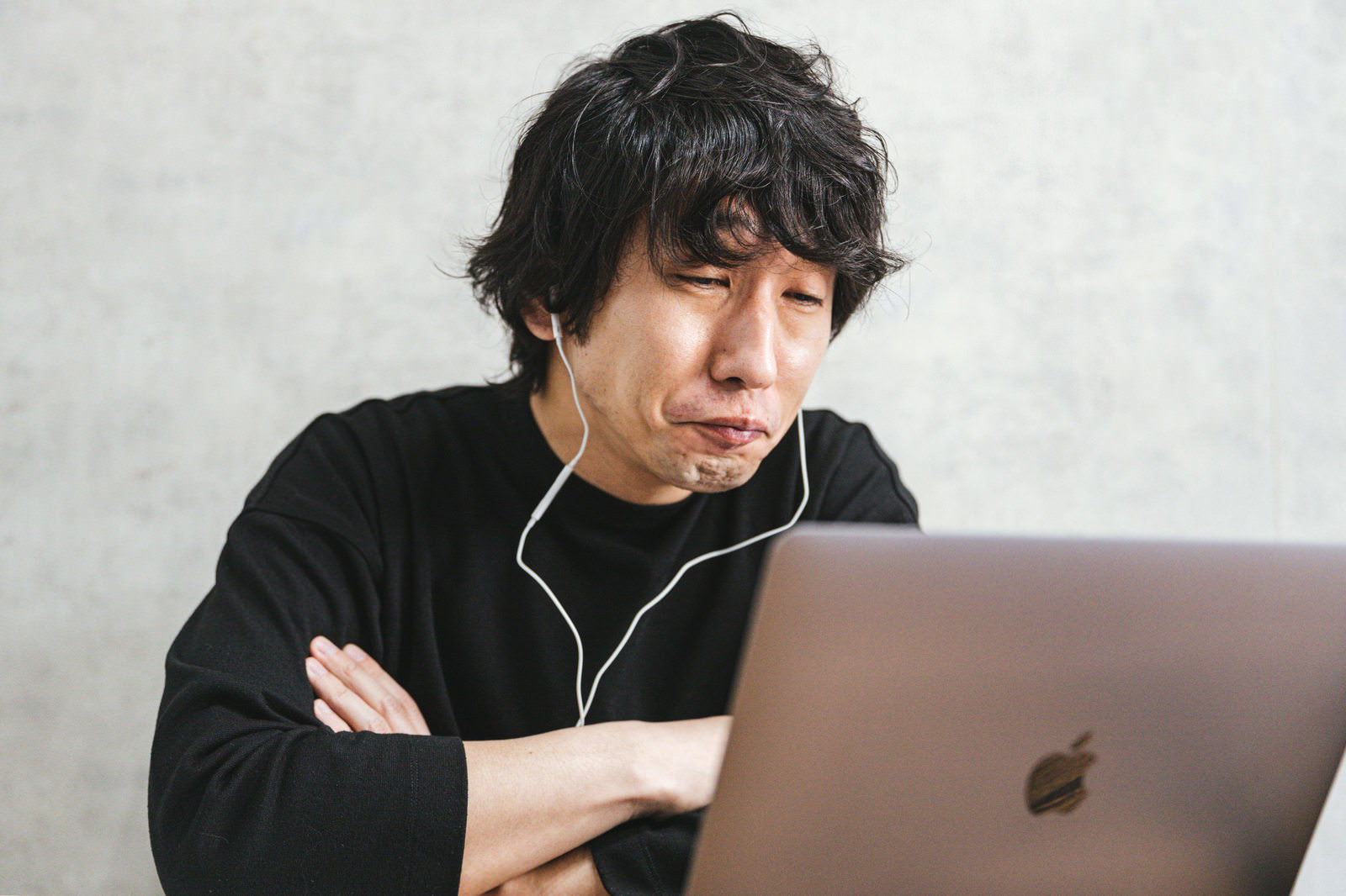 パソコン作業中に困った表情を見せる黒いトレーナーの男性［モデル：大川竜弥］