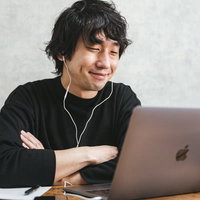 トラブル解決後にパソコンの前で腕を組んでニンマリの男性の写真