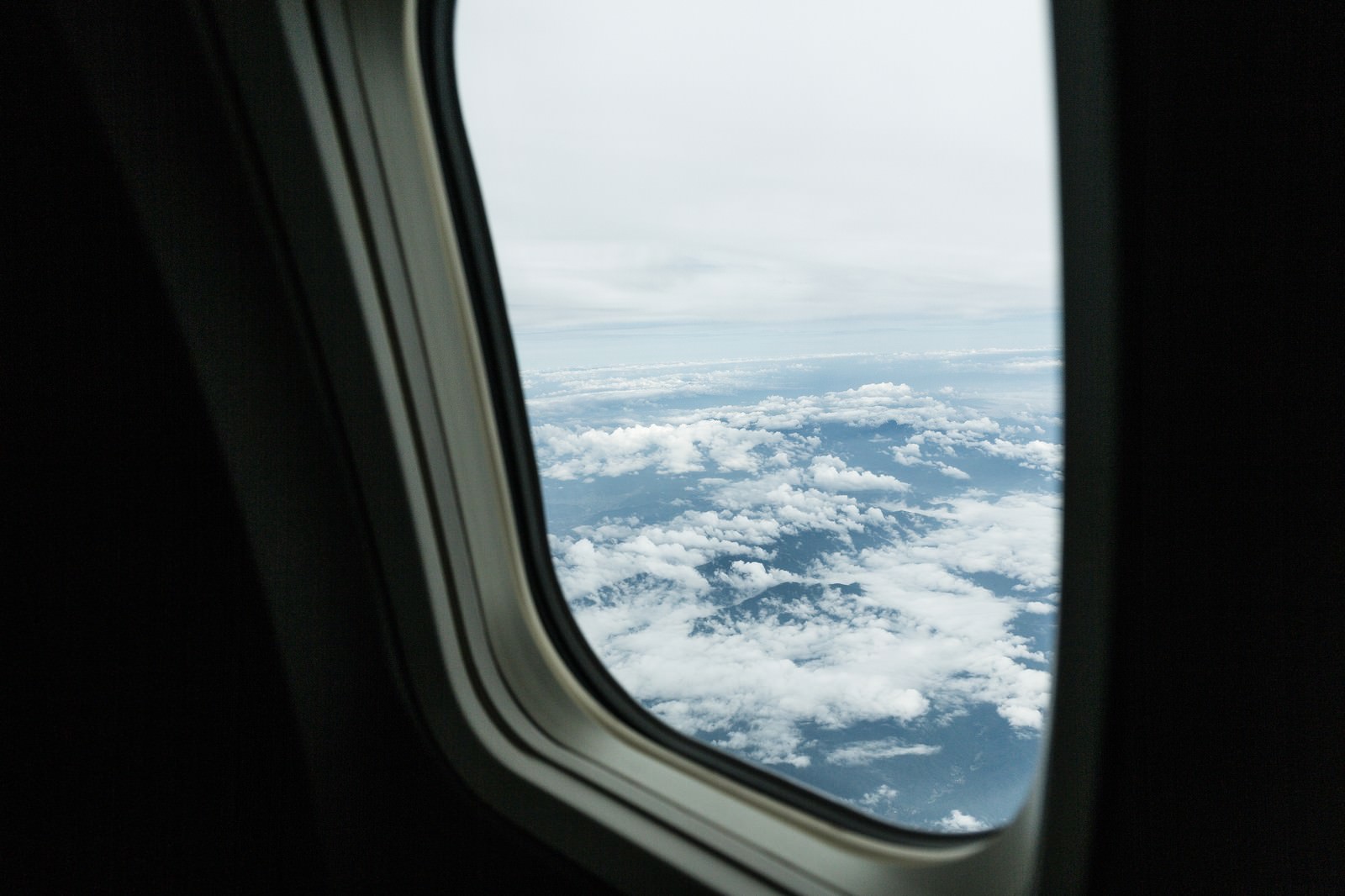 旅客機の窓から眼下に広がる雲海と青空を見下ろした景色