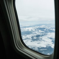 旅客機の窓から見える上空の雲海と青空の写真