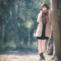 秋の公園で木にもたれかかる彼女の待ちぼうけシーンの写真