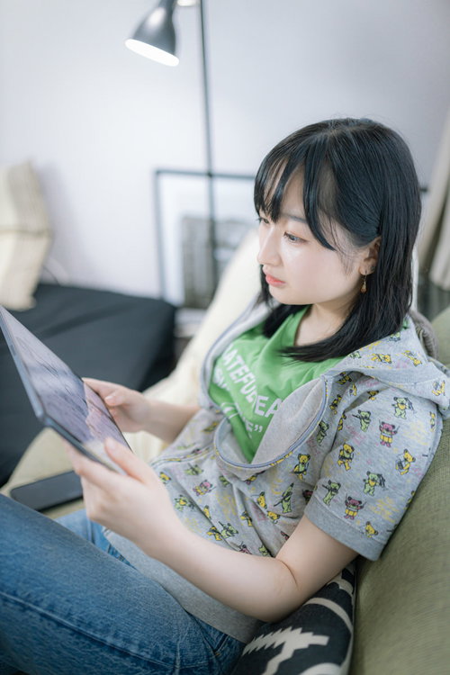 ソファーでタブレット端末を持ってコミックスを楽しむ女性