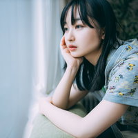 窓際で頬杖をつき外出自粛の中で憂鬱な表情を浮かべる女性の写真