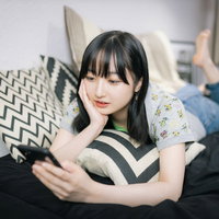 ソファーで寝転んでスマホを見るスマホ女子の写真