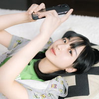 ベッドで横たわってスマホを操作するリラックス女子の写真