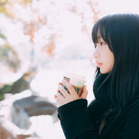 寒い屋外でホットドリンクを飲んで一息つく女性の写真