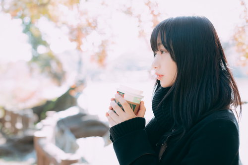 寒い屋外でホットドリンクを飲んで一息つく女性