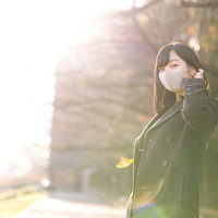 黄昏時にマスクをしたコート姿の女性が振り返るの写真