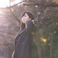 後ろに髪を流すマスク女子の日向ぼっこ、屋外での花粉症対策の写真