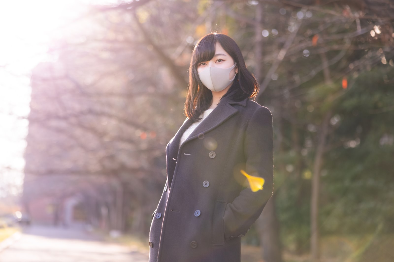 コートのポケットに手を入れてマスクを着用した女性［モデル：井隼そら］