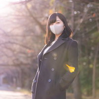 コートのポケットに手を入れるマスク女子の日向ぼっこの写真