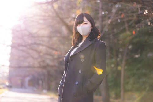 コートのポケットに手を入れるマスク女子の日向ぼっこ