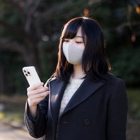また勧誘系のLINEか・・・とスマホを見て呆れるマスク女子の写真
