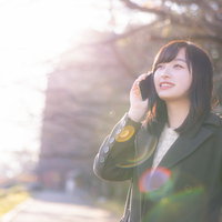 公園で携帯電話をかけて通話する女性、待ち合わせシーンの写真