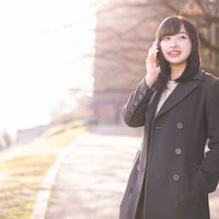 ポケットに片手を入れてもしもしと通話中の女性の写真