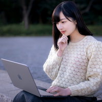 外出先でノートパソコンを覗き込んで考える女性の写真