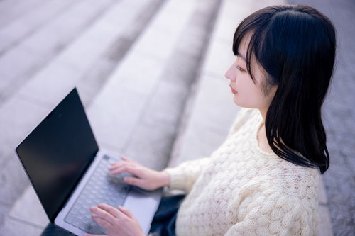 Macbookでコーディングする女子エンジニア