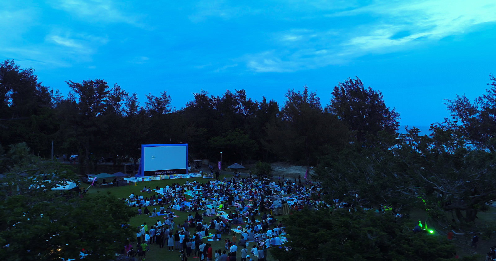 夕暮れの青い空の下で野外映画を楽しむ観客たち