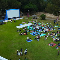 徳之島の野外映画イベントでレジャーシートを敷いて放映を待つ人々の写真