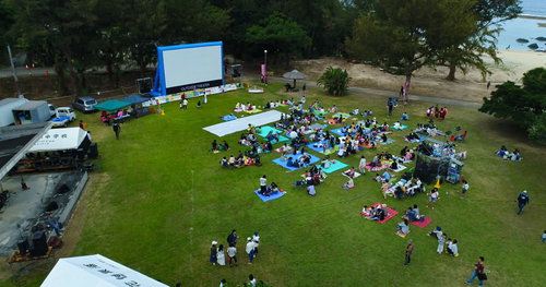 徳之島の野外映画イベントでレジャーシートを敷いて放映を待つ人々