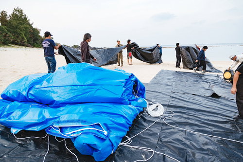 徳之島のソラシネで巨大スクリーンを搬出する作業員たち
