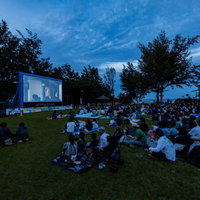 夕暮れの芝生広場で野外映画を鑑賞する人々の写真