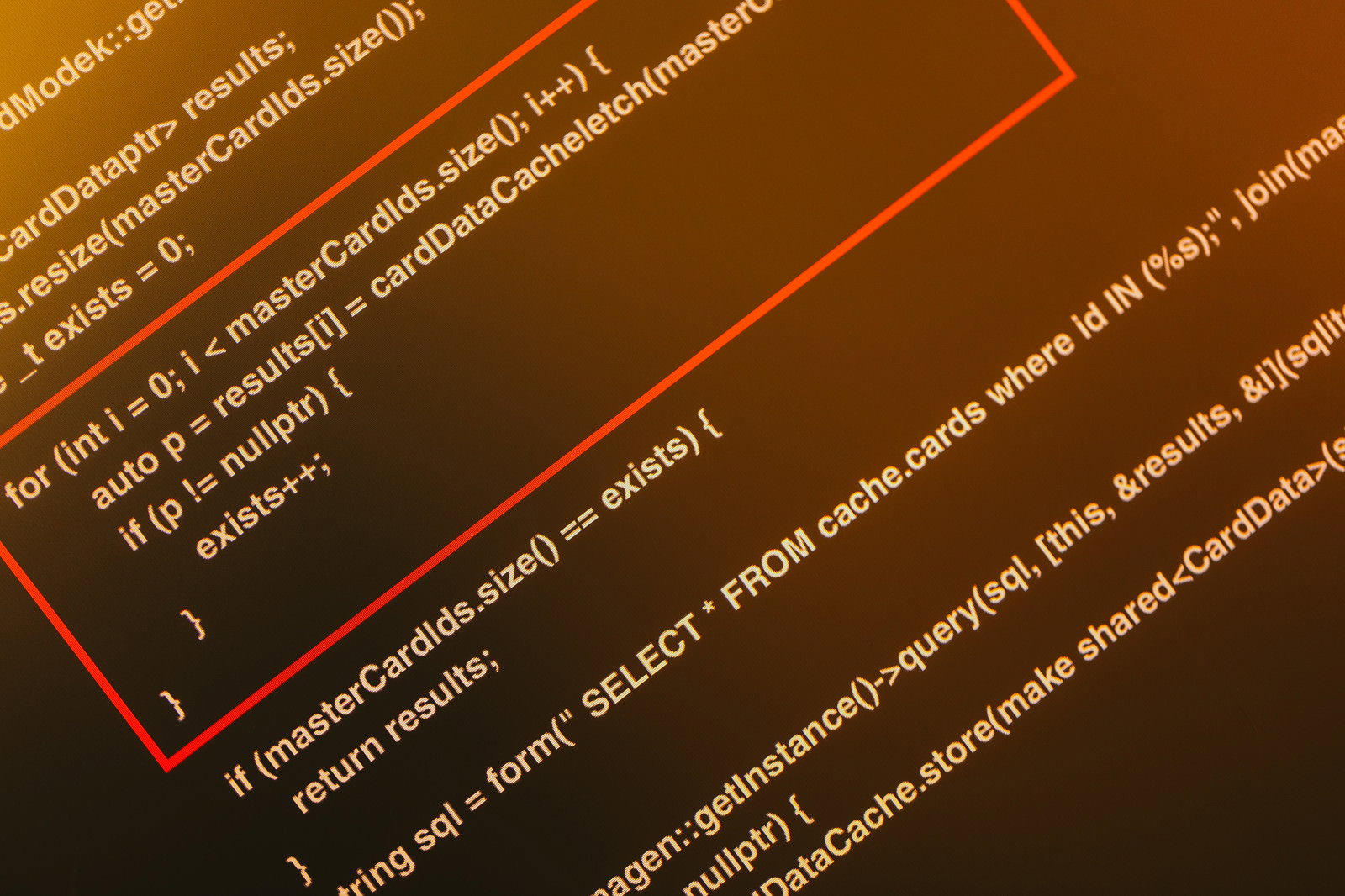 オレンジ色の背景にソースコードが表示されたモニター画面