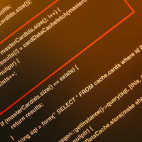 オレンジ背景に表示されたソースコードとモニターの写真