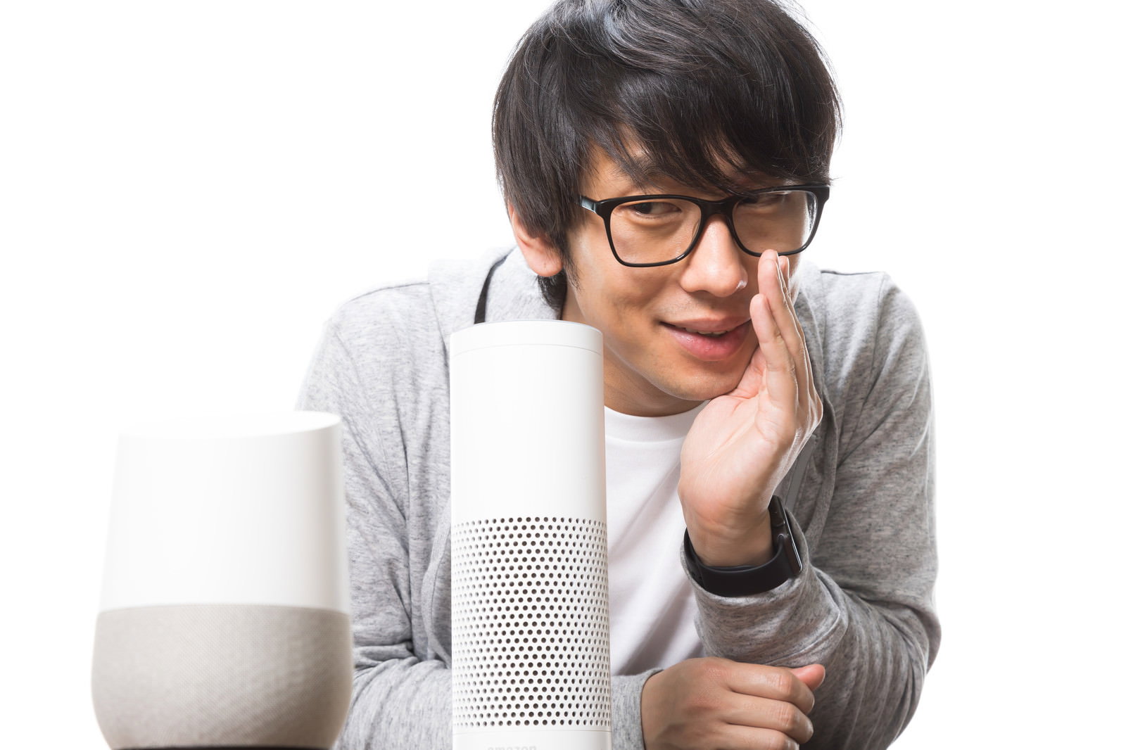 白いスマートスピーカーに向かって話しかけるメガネをかけた男性