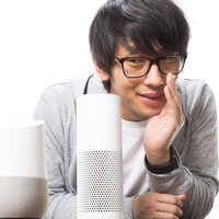 スマートスピーカーに声をかけるメガネをかけた男性の写真