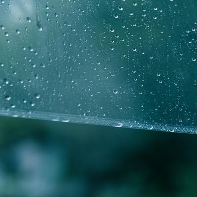 透明なビニール傘の表面に付いた雨粒のクローズアップの写真