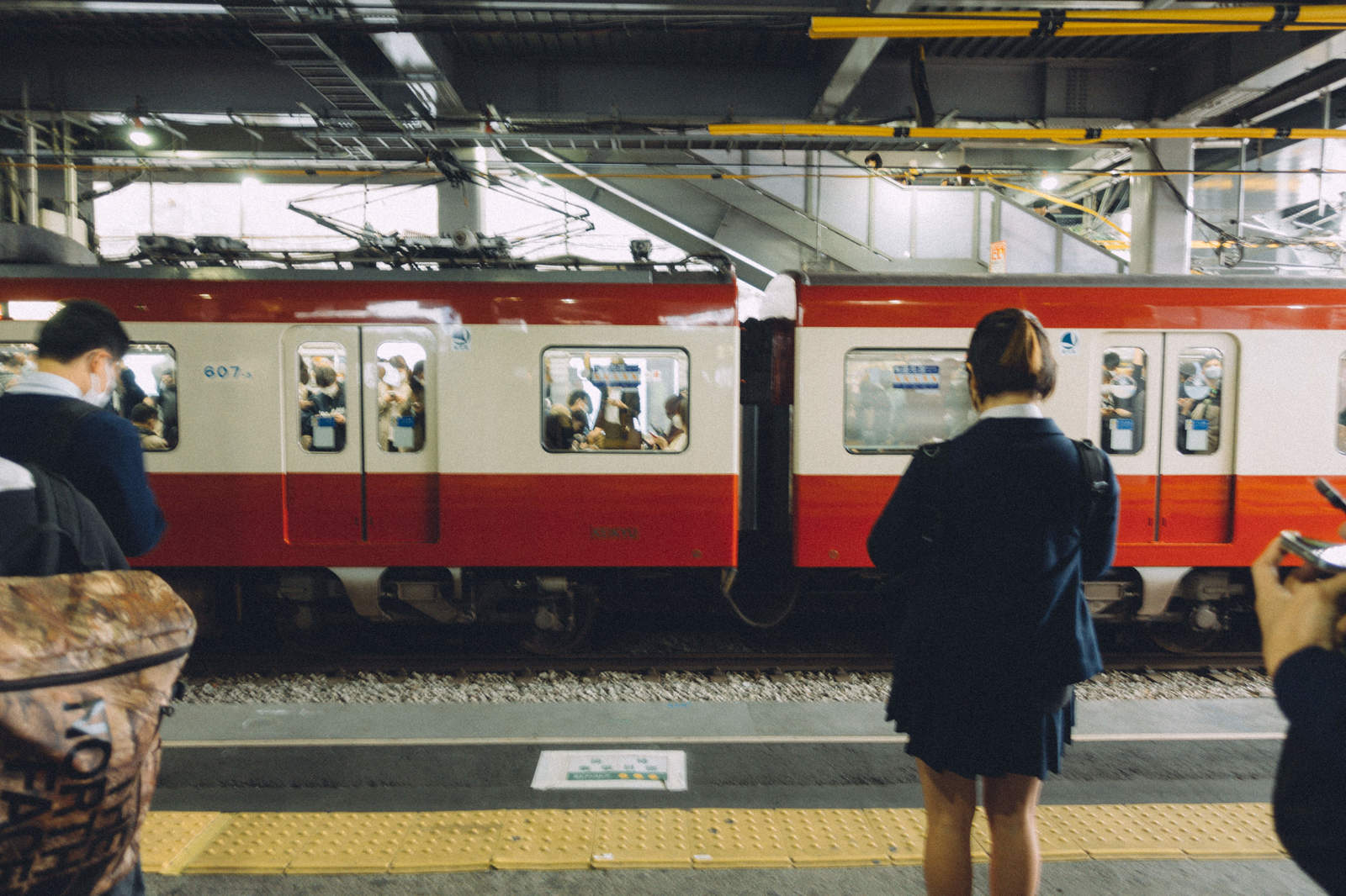 京急線のホームで電車を待つ制服姿の学生たち