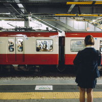 京急線のホームに並んで電車を待つ学生たちの写真