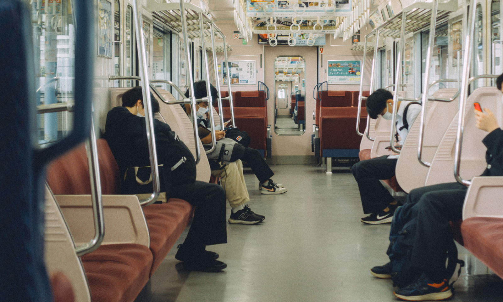 昼間の電車の車内で乗客が少なく赤茶色のシートが見える