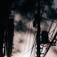 電柱と電線が絡み合う不穏な曇り空の風景の写真